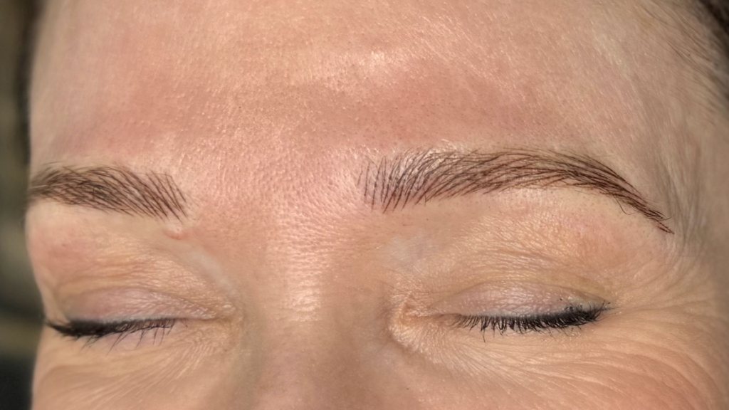 Close-up of a client&rsquo;s eyebrows after a hairstroke brow treatment, showing soft, natural-looking strokes with eyes closed.